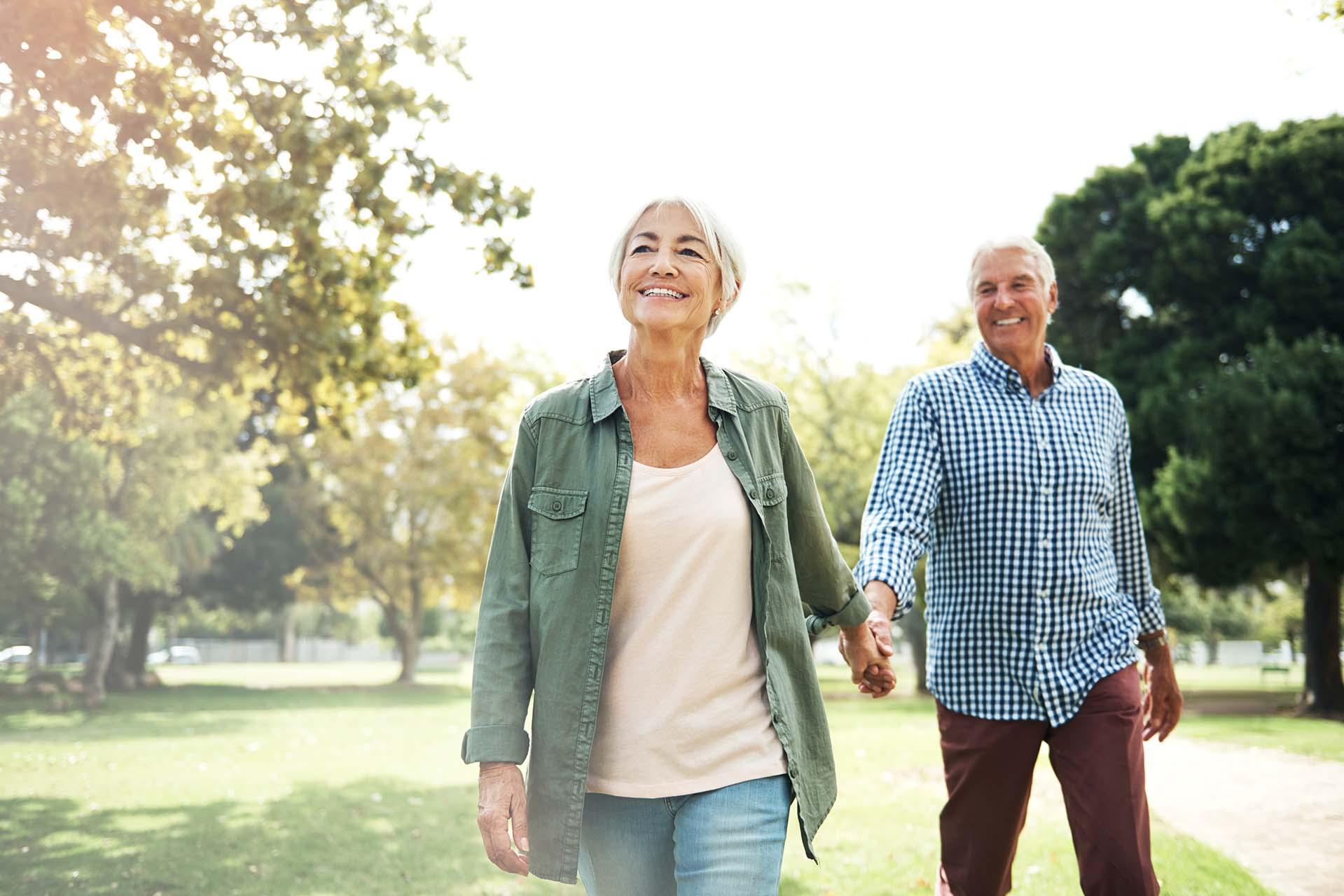 Ein fittes älteres Paar spaziert fröhlich durch einen Park