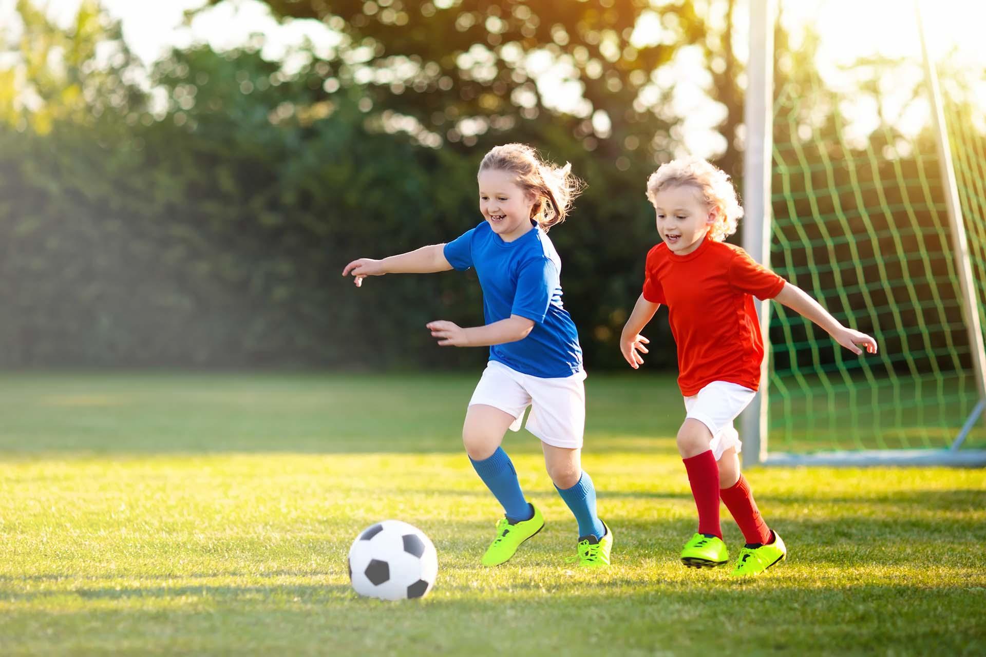 Ein kleiner Junge spielt mit einem kleinen Mädchen Fußball